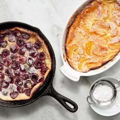 a baked dish in a cast iron skillet next to a bowl of powdered sugar