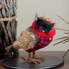 a stuffed animal bird wearing a red and black plaid shirt on top of a wooden table