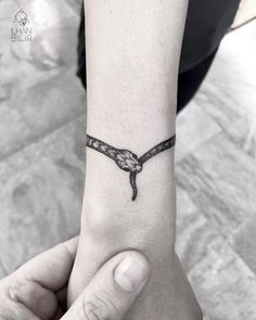 a woman's wrist tattoo with a snake on the middle part of her arm