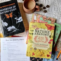 two books and some coffee on a table with paper, pencils and other items