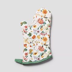 a oven mitt with flowers on the front and green trimmings, sitting on top of a gray surface