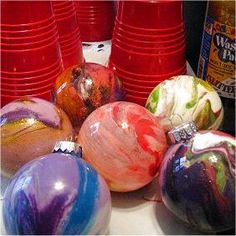 there are many different colored balls on the table with red cups in front of them