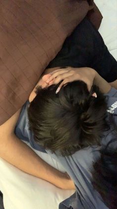 a woman laying on top of a bed next to a brown pillow with her head down