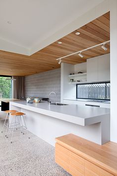 an open kitchen and dining area with white counter tops, wood paneling on the ceiling