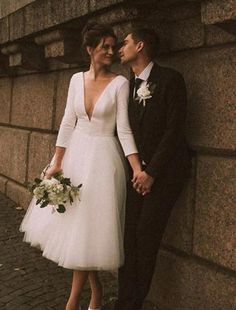 a bride and groom leaning against a stone wall