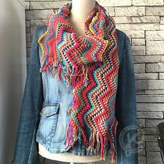 a multicolored knitted scarf hanging on a mannequin