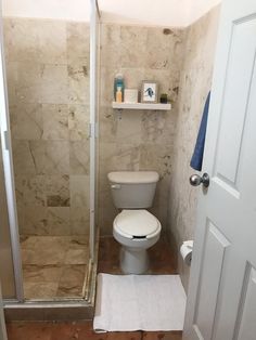 a bathroom with a toilet, shower and towel rack on the wall next to the door