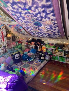 a room filled with lots of stuffed animals under a colorful tarp over the bed