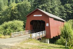 a red covered bridge with trees in the background