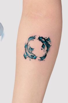 a small tattoo on the leg of a woman's arm with two dolphins in it