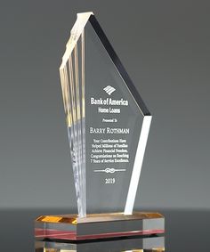 a glass award is displayed on a black table with a gray back ground behind it