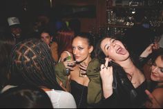 two young women laughing and having fun at a club or bar while others look on