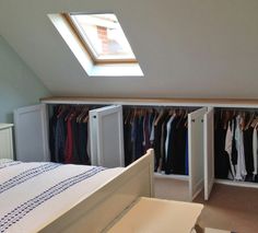 an attic bedroom with closets and clothes on hangers