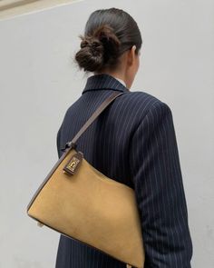 a woman in a suit carrying a brown purse