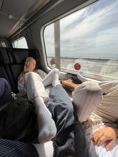 two people sleeping in the back of a van on a road next to the ocean