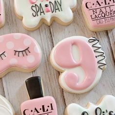 decorated cookies with pink and white icing are arranged on a wooden surface, including the number nine