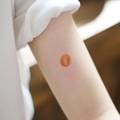 an orange tattoo on the arm of a woman's left arm, which has a small piece of fruit in it