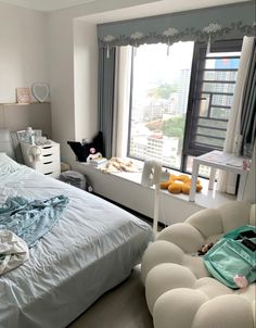 a bed room with a neatly made bed next to a large window and a chair