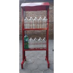 a red shelf with bottles on it and a brick wall in the backround