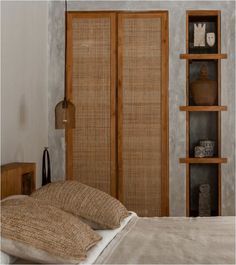 a bed sitting next to a wooden book shelf on top of a white wall in a bedroom