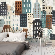 a bed sitting next to a wall covered in cityscapes on top of a wooden floor