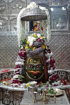 an elaborately decorated shrine with flowers on the side and a mask in the center