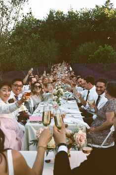 a group of people sitting at a long table with wine glasses in front of them