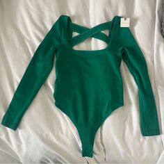 a green bodysuit laying on top of a white sheet with no clothing underneath it