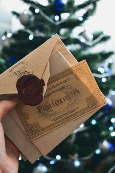 a person holding an envelope with a wax stamp on it in front of a christmas tree