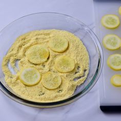 a glass bowl filled with sliced lemons on top of a white tablecloth next to a cutting board