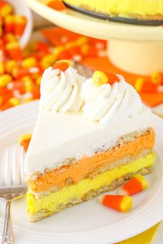 a slice of cake with white frosting and candy corn on the side sitting on a plate