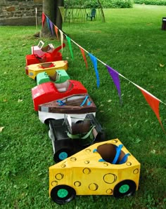 a row of toy cars sitting on top of a lush green field