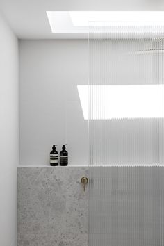 two black and white vases are on the wall in this modern bathroom with glass doors