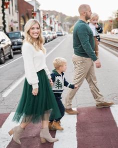 a family crossing the street with their toddler holding hands and walking across the crosswalk