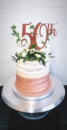 a white and pink cake sitting on top of a metal platter with the number 50 on it