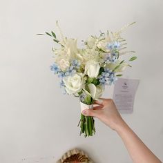 a woman holding a bouquet of white and blue flowers