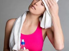 a woman in a pink sports bra holding a towel over her head