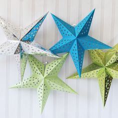 three origami stars hanging on the wall, one is green and one is blue