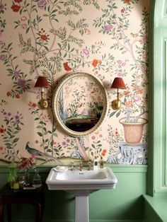 a bathroom sink sitting under a mirror next to a wall mounted faucet with flowers on it