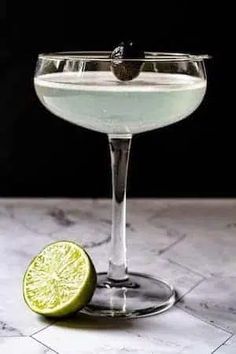 a martini glass with a lime on the rim and a slice of lime next to it