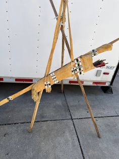 a large wooden sculpture sitting on top of a cement floor next to a white trailer