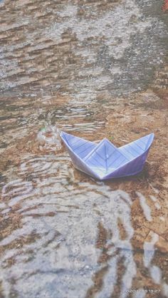 a small paper boat floating on top of a body of water next to a wall