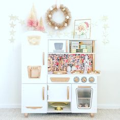 an old fashioned wooden toy stove and oven in a child's play room with christmas decorations on the wall