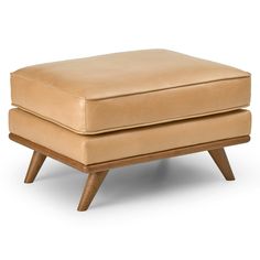 a tan leather ottoman with wooden legs on an isolated white background for use as a footstool