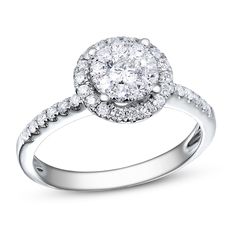 a white gold ring with diamonds on the band and an oval halo setting in the center