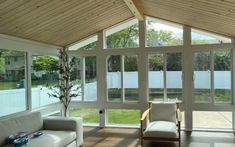 a living room filled with furniture and lots of glass doors on the windows letting in light