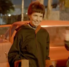 a woman standing in front of an orange car