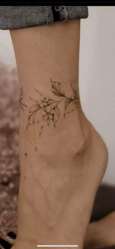 a woman's foot with a flower tattoo on the side of her leg and ankle