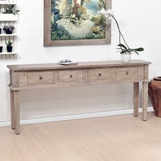 a painting hangs on the wall above a table with two drawers and a phone sitting on it