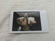 a polaroid photo of a person making the middle finger sign with their hand and fingers